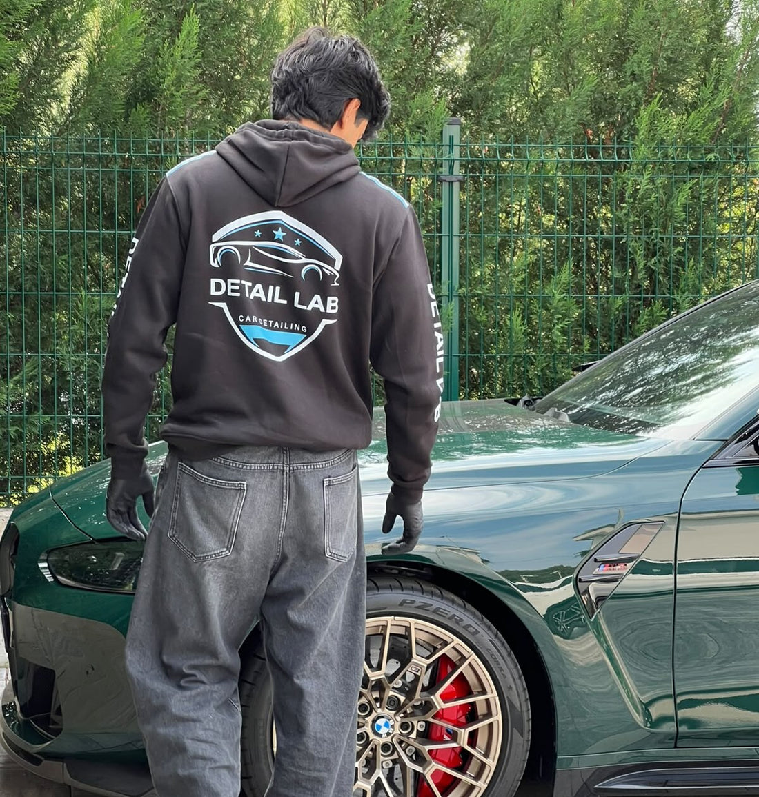 Detailer Detail Lab con la felpa del team accanto a una BMW verde appena trattata